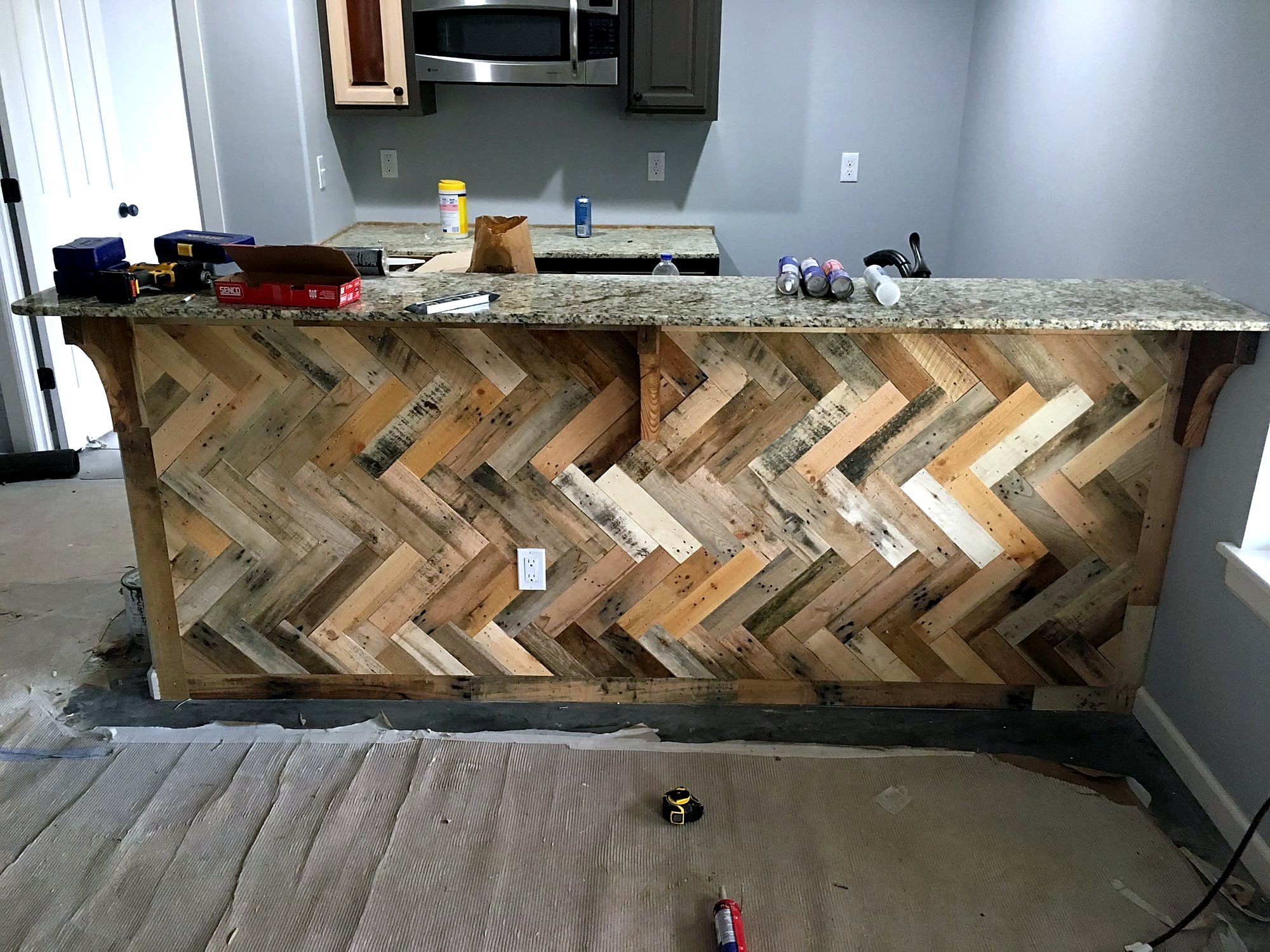 Kitchen island with a chevron-patterned reclaimed wood face and a polished granite countertop