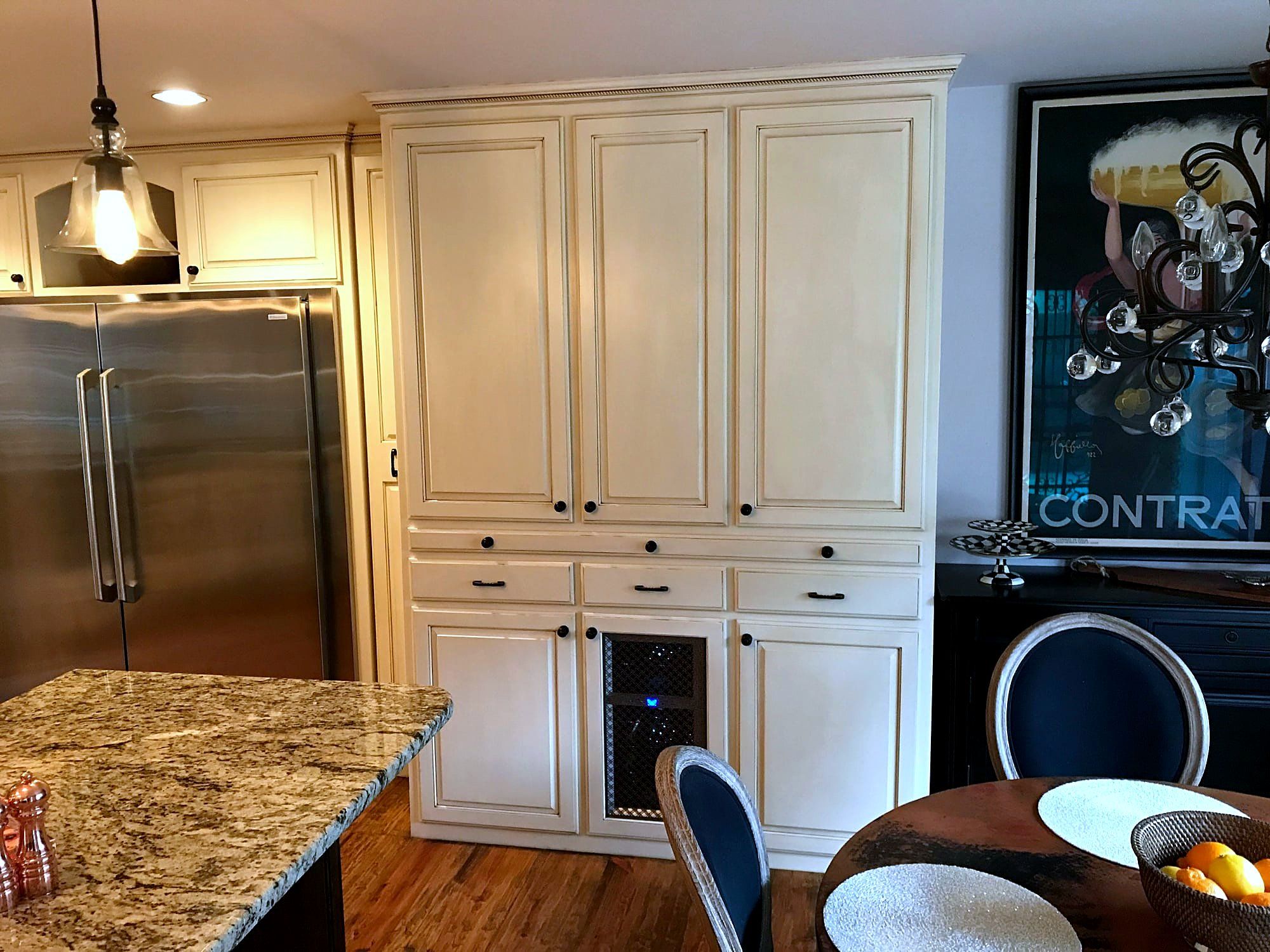 Cream cabinetry kitchen with a built-in wine cooler, stainless refrigerator, and granite island