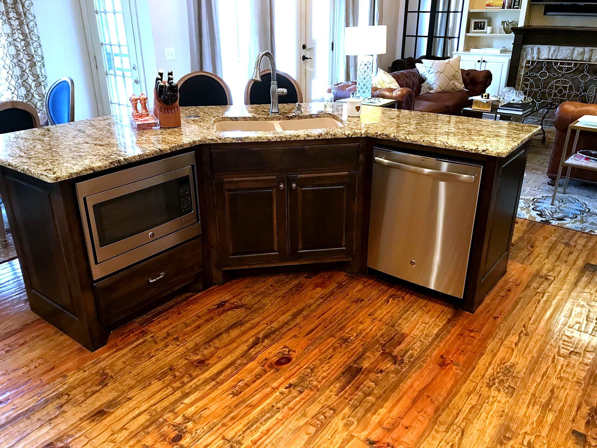 L-shaped dark wood kitchen island with a granite countertop, built-in microwave, and dishwasher