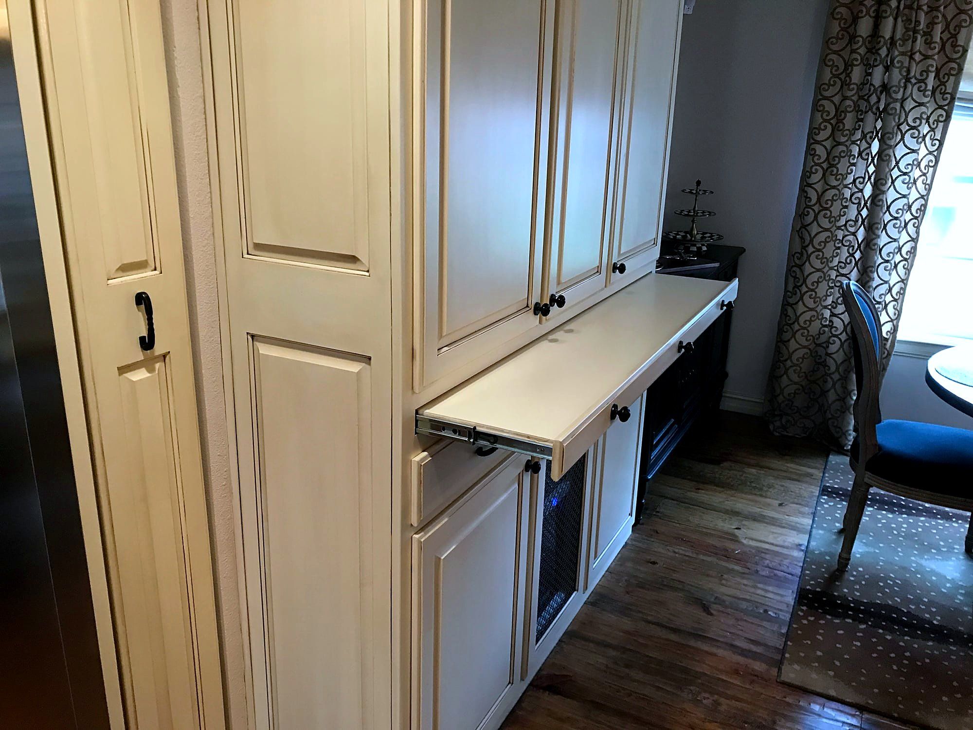 Cream cabinetry with a pull-out countertop extension in a kitchen bar area