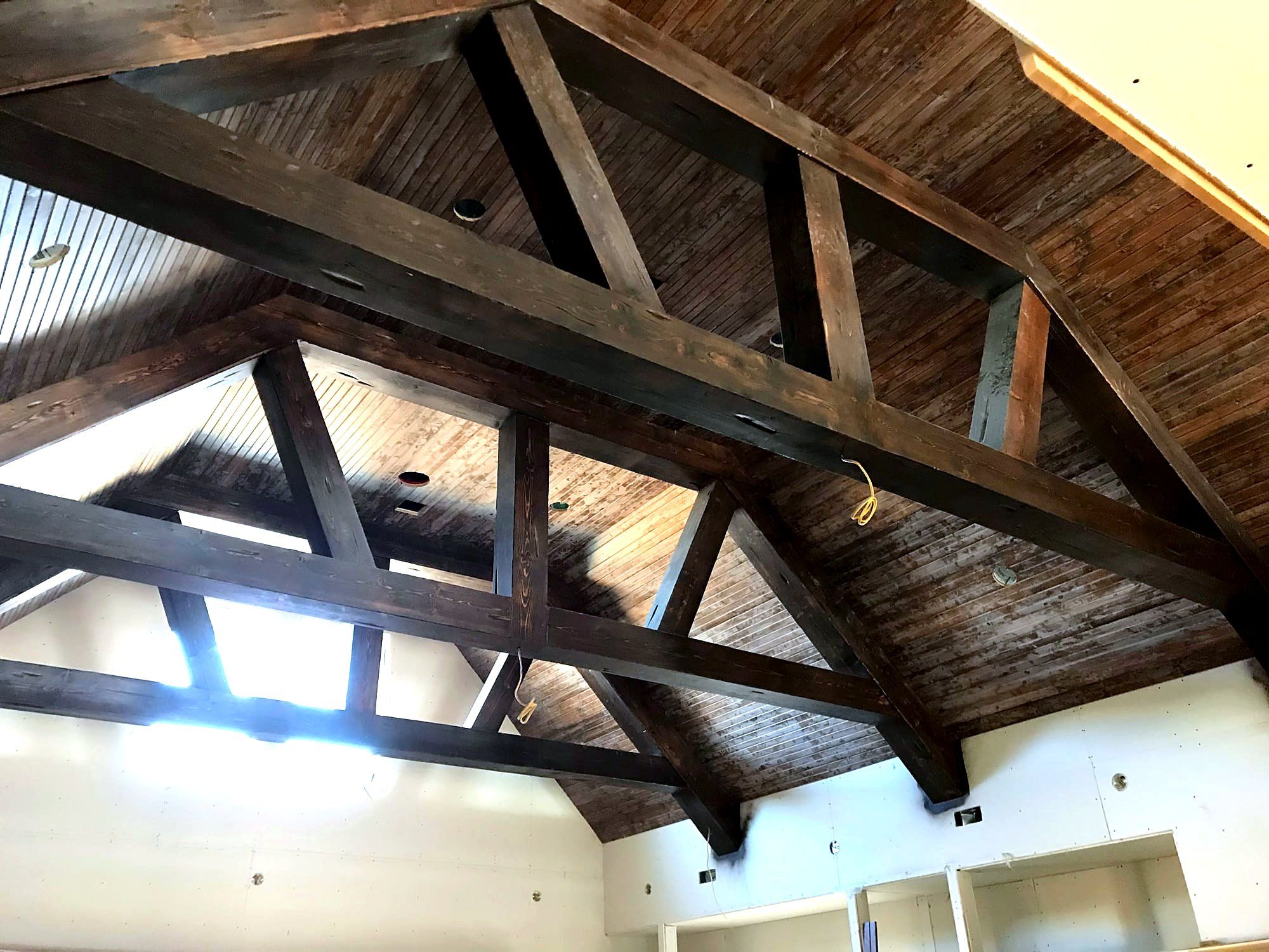 Vaulted tongue-and-groove wood ceiling with a king-post truss, skylights, and recessed lighting
