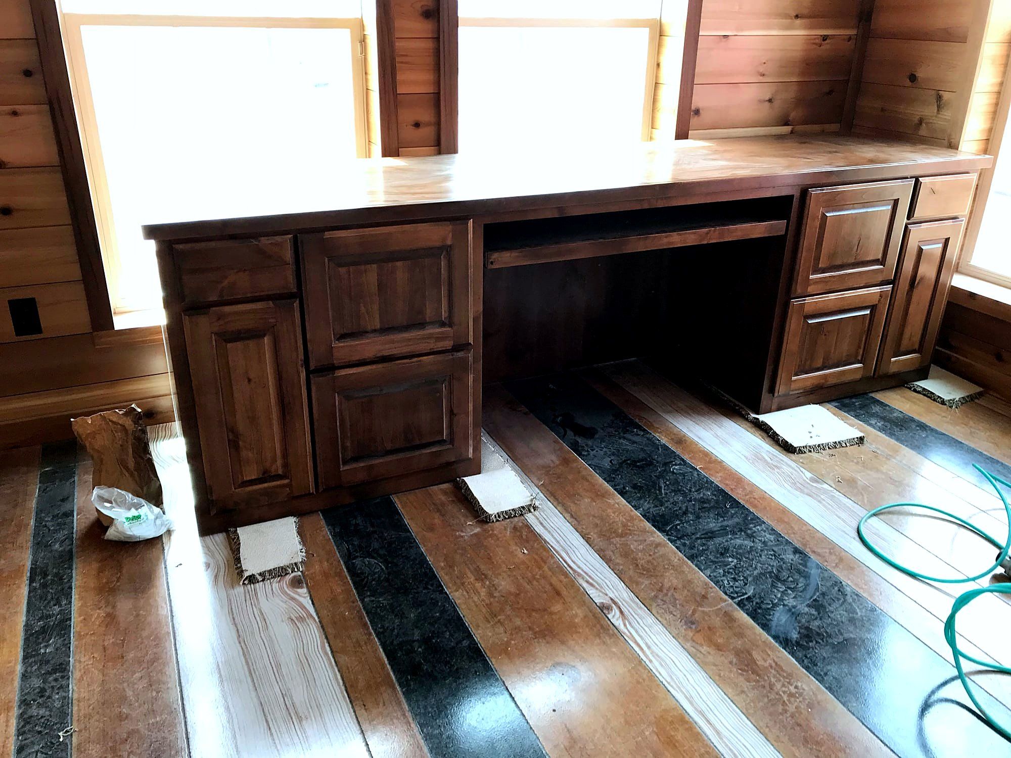 Built-in wood desk with drawers set into a knotty pine wall in a cabin-style office