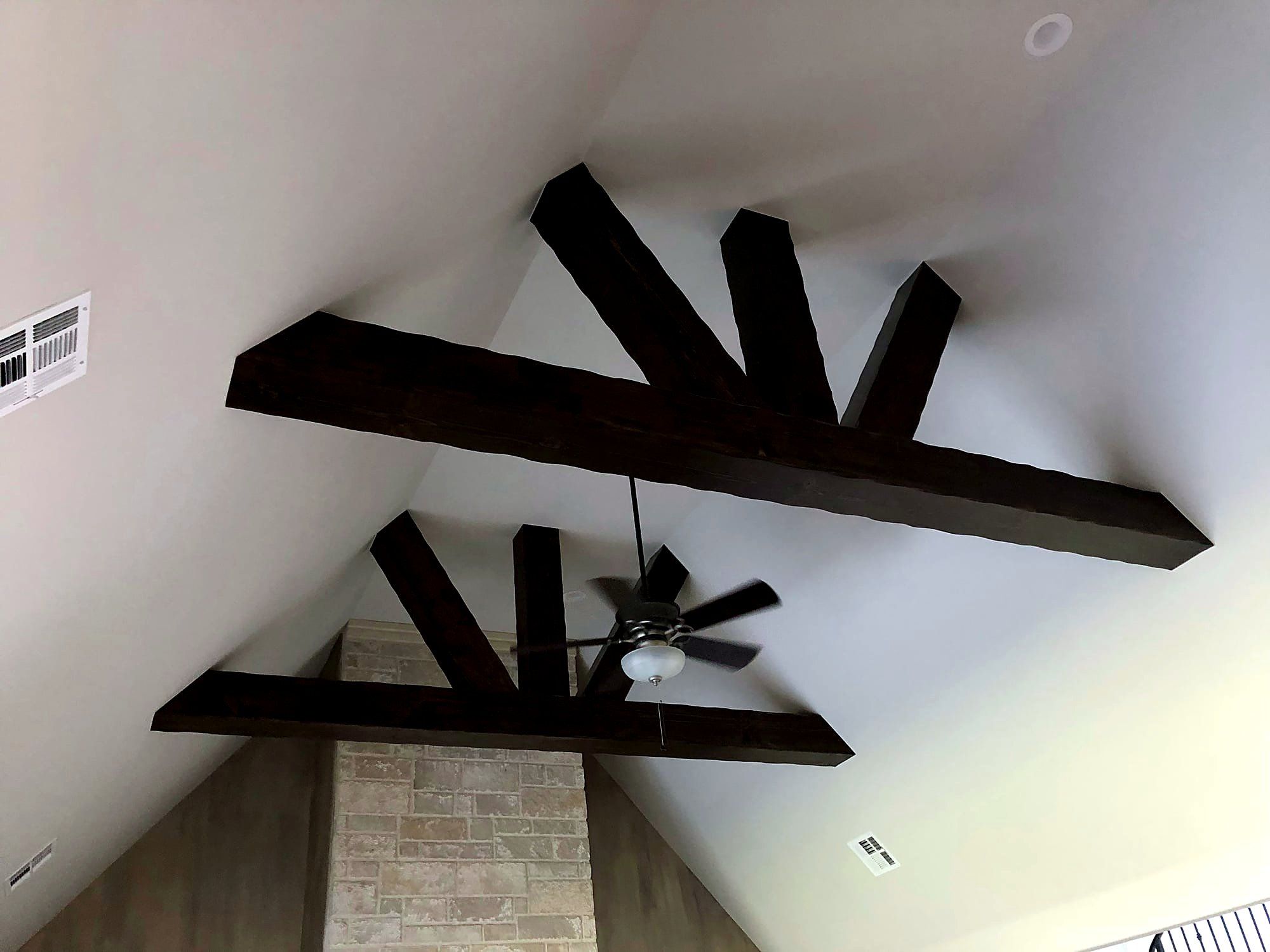 Exposed ceiling beams fanning out in a sunburst pattern around a mounted ceiling fan
