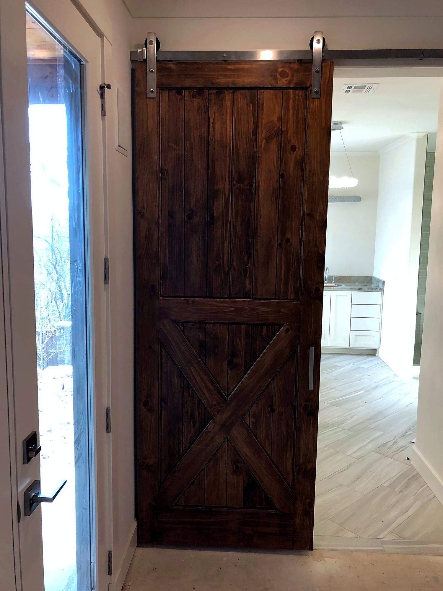 Dark stained sliding barn door with an X-brace pattern and black rail hardware