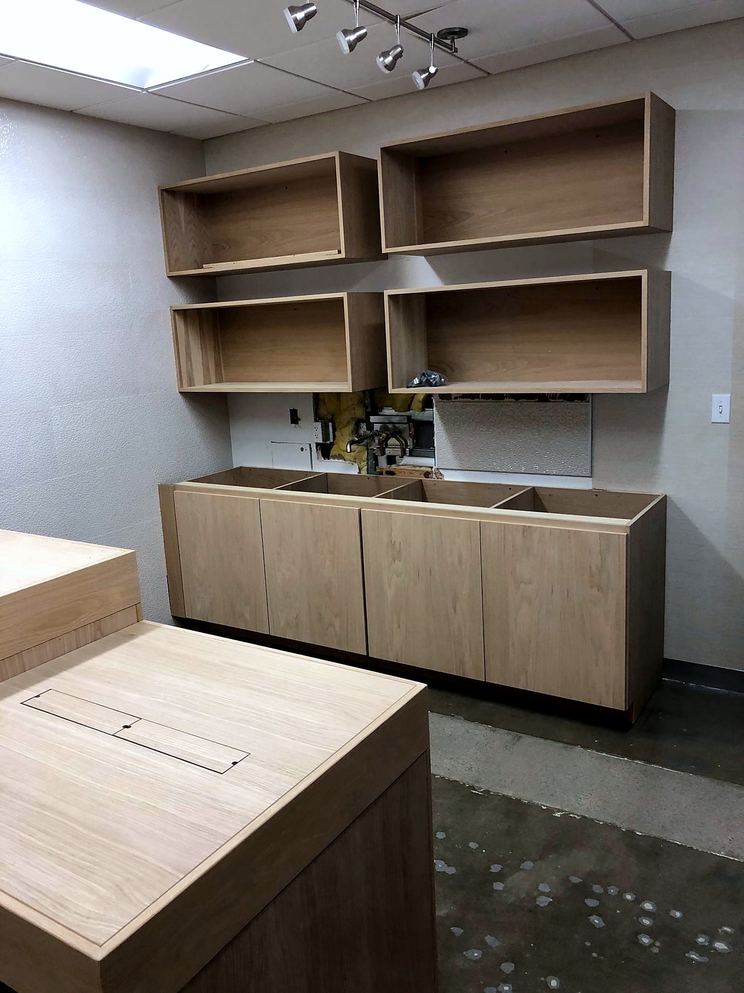 Floating wood wall cabinets over a built-in counter with a cutout for cable pass-through
