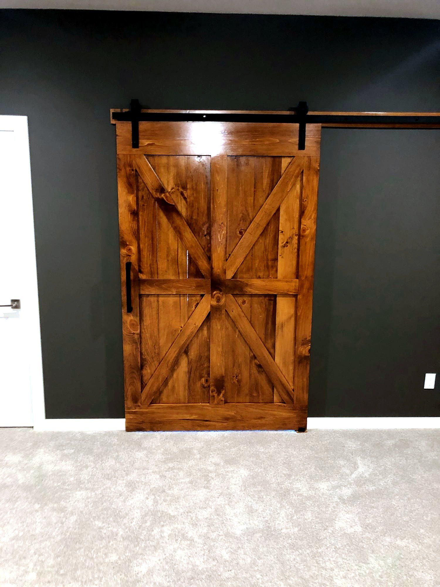 Dark walnut-stained sliding barn door with an X-brace pattern on black hardware