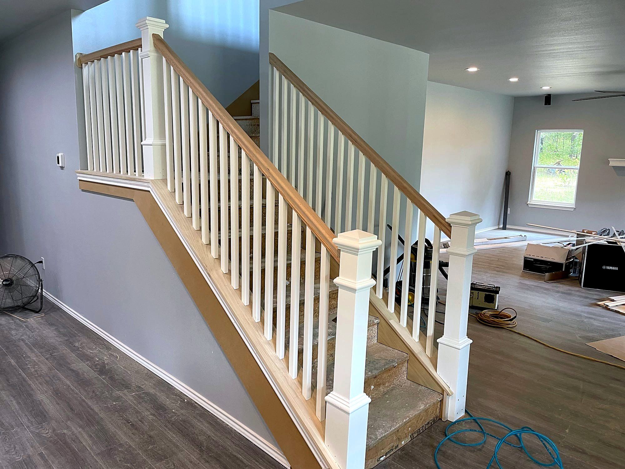 Staircase with white painted balusters, a dark wood handrail, and a carpet runner