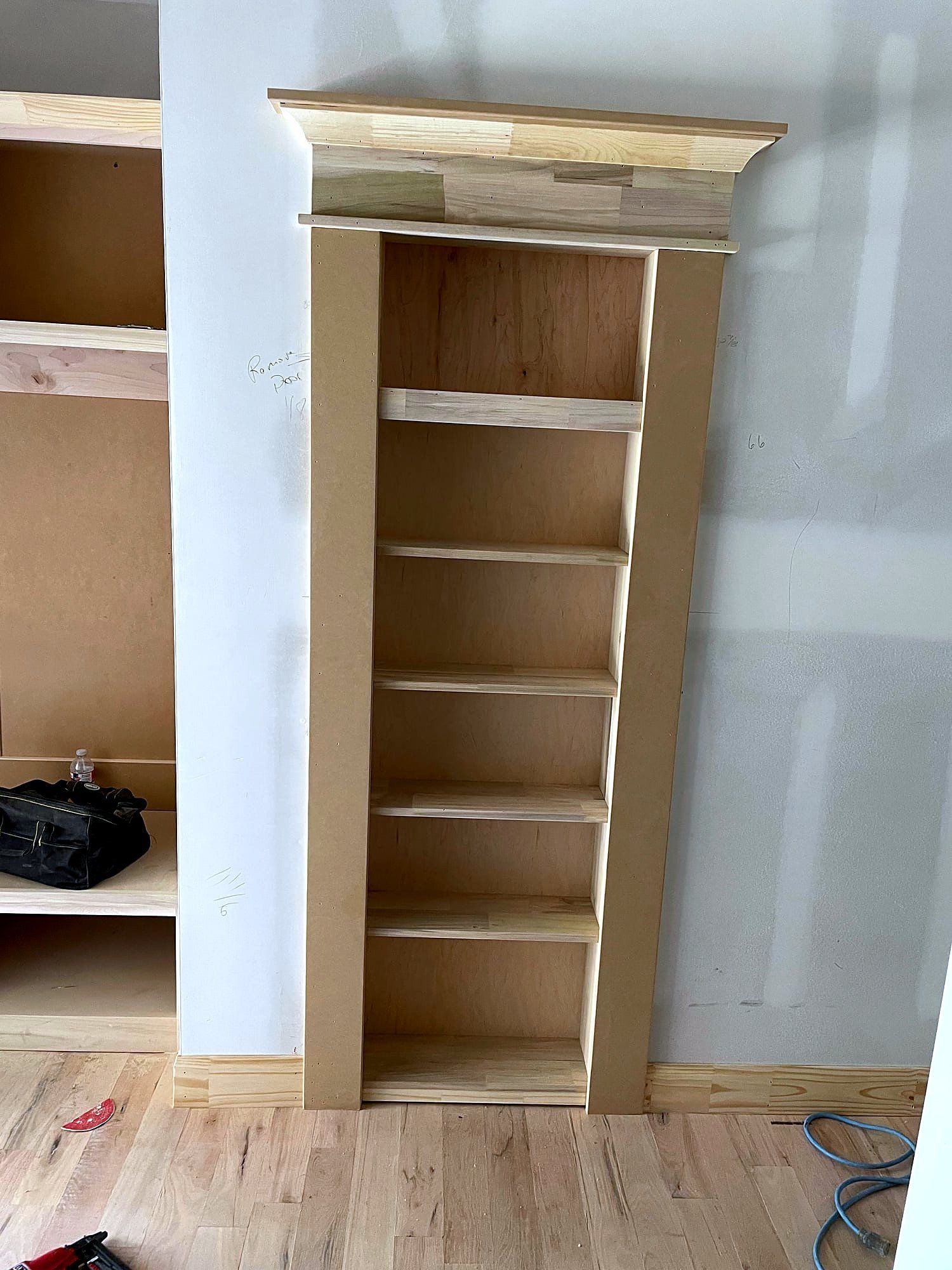 Built-in bookcase with a crown-topped face frame and adjustable pine shelves, fitted into a wall alcove, unstained