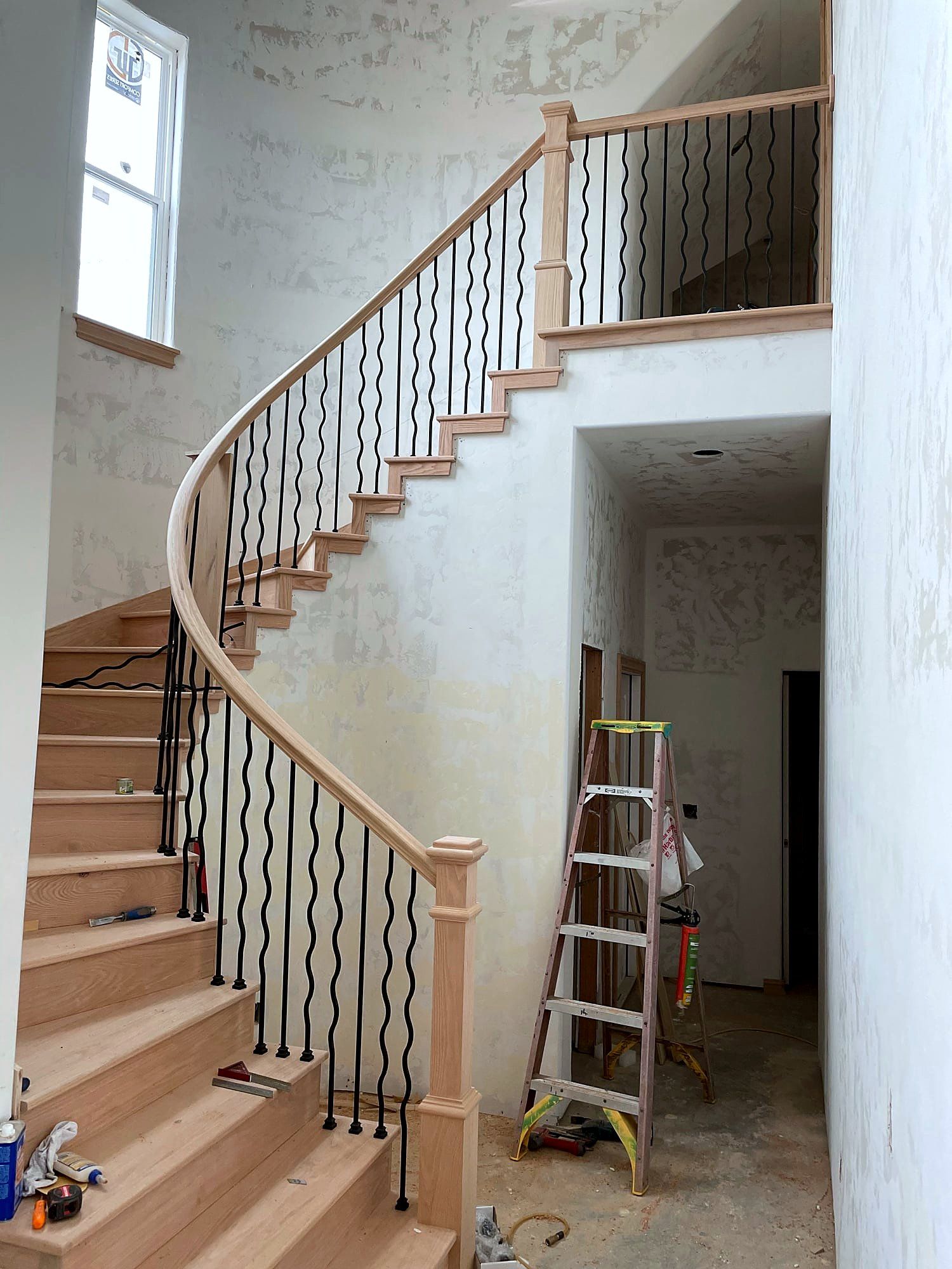 Curved staircase with wave-pattern iron balusters and a wood handrail and treads