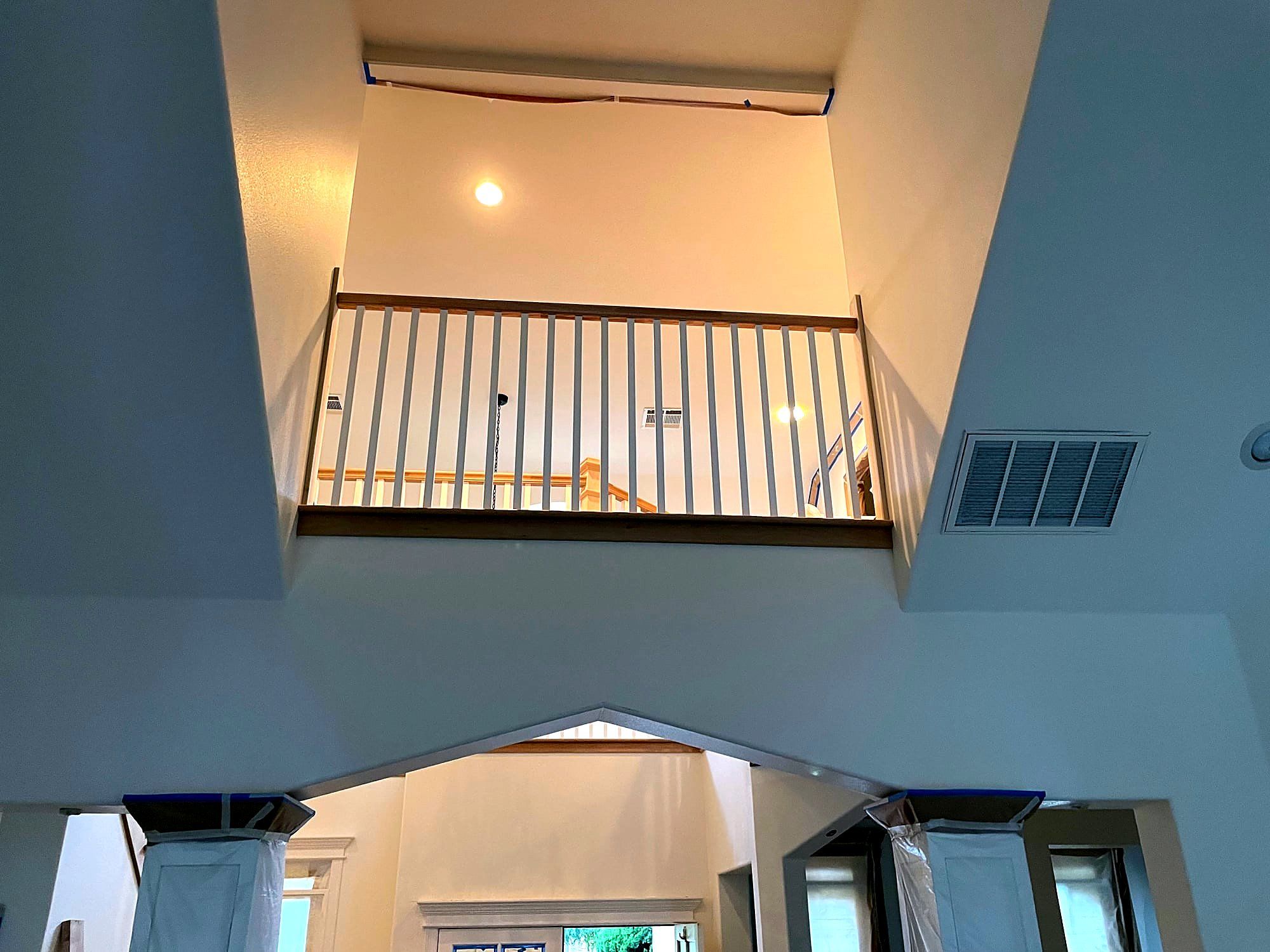 Second-floor balcony railing with white balusters overlooking a stairwell