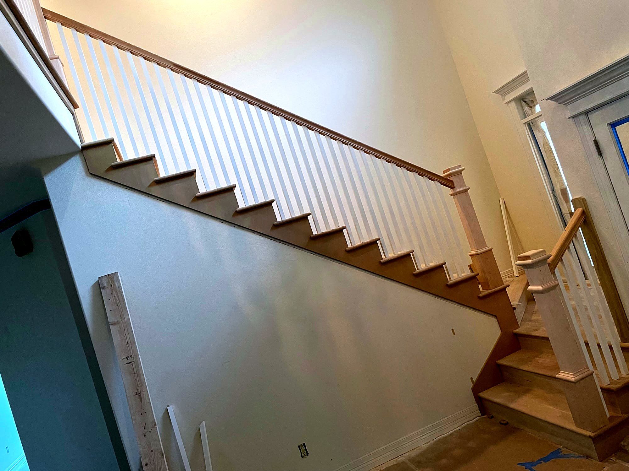 Staircase with painted white risers, dark wood treads, and a matching handrail