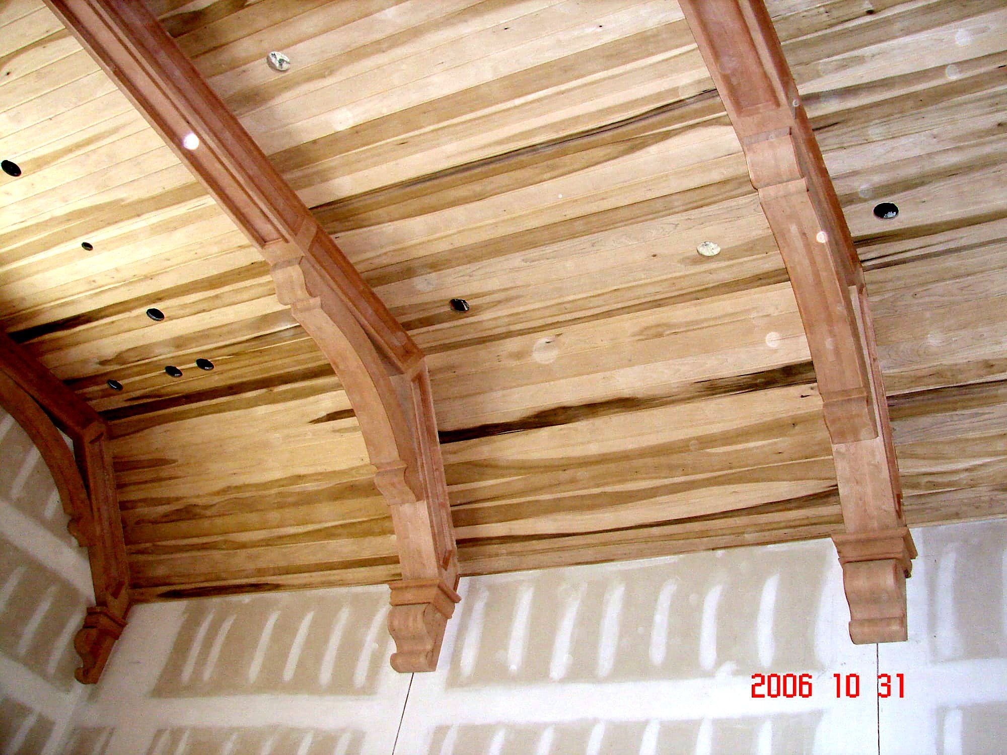 Curved cove ceiling detail with carved wood corbel brackets supporting the arch, natural finish tongue-and-groove boards