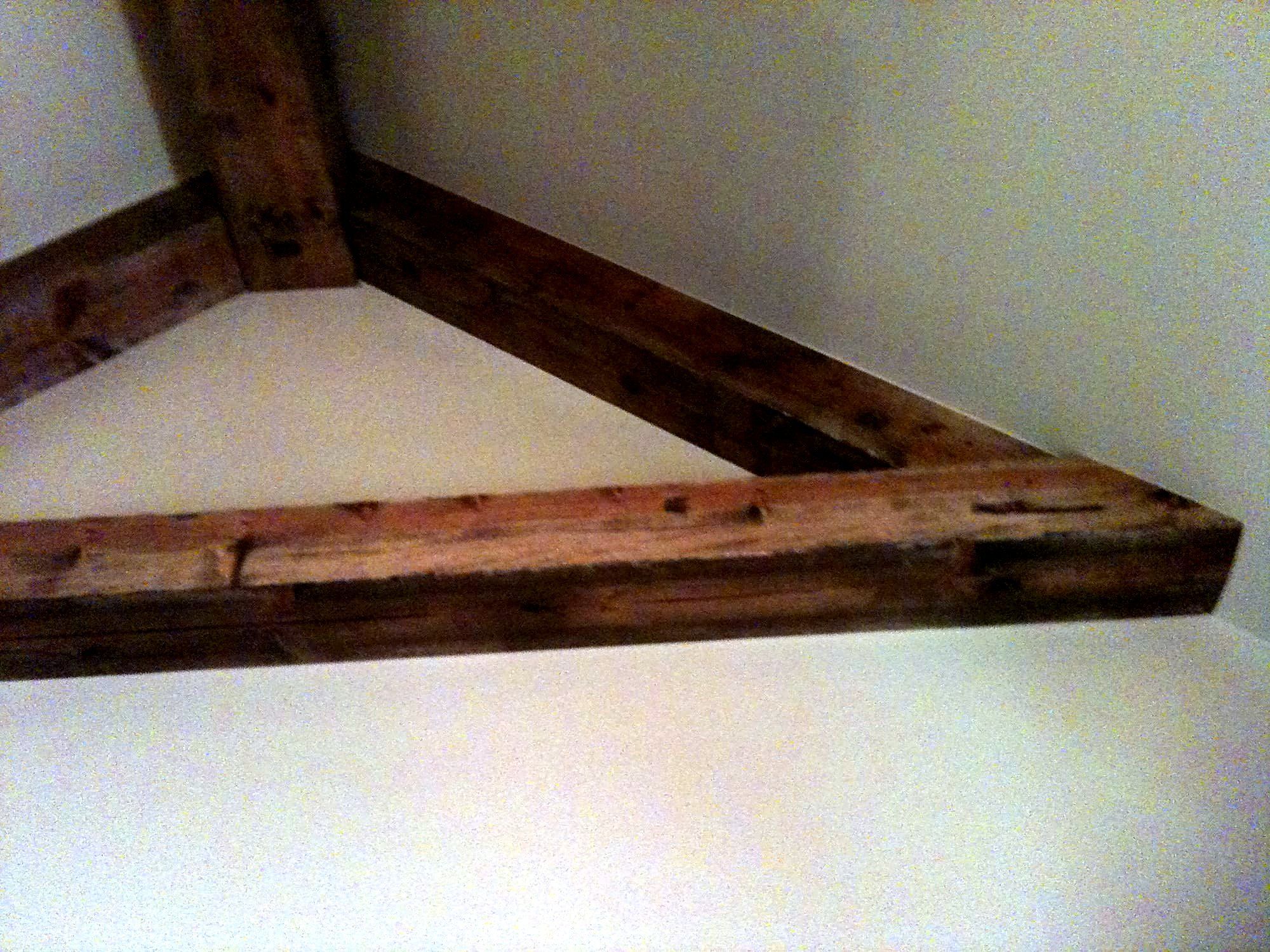 Single exposed wood beam with a knee-brace bracket mounted to a painted wall